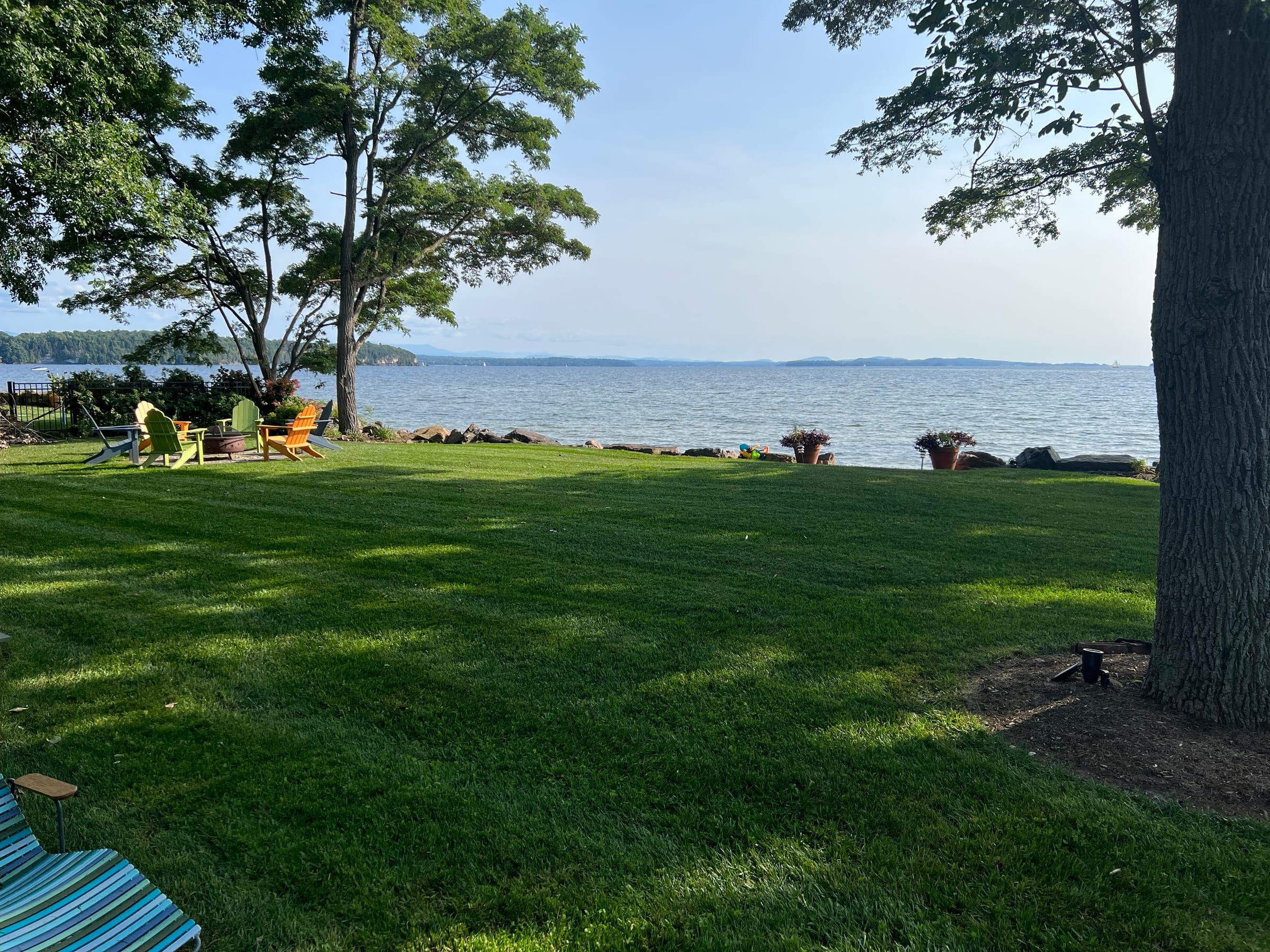 A thick green lawn running down to the lake, with chairs set out by the water