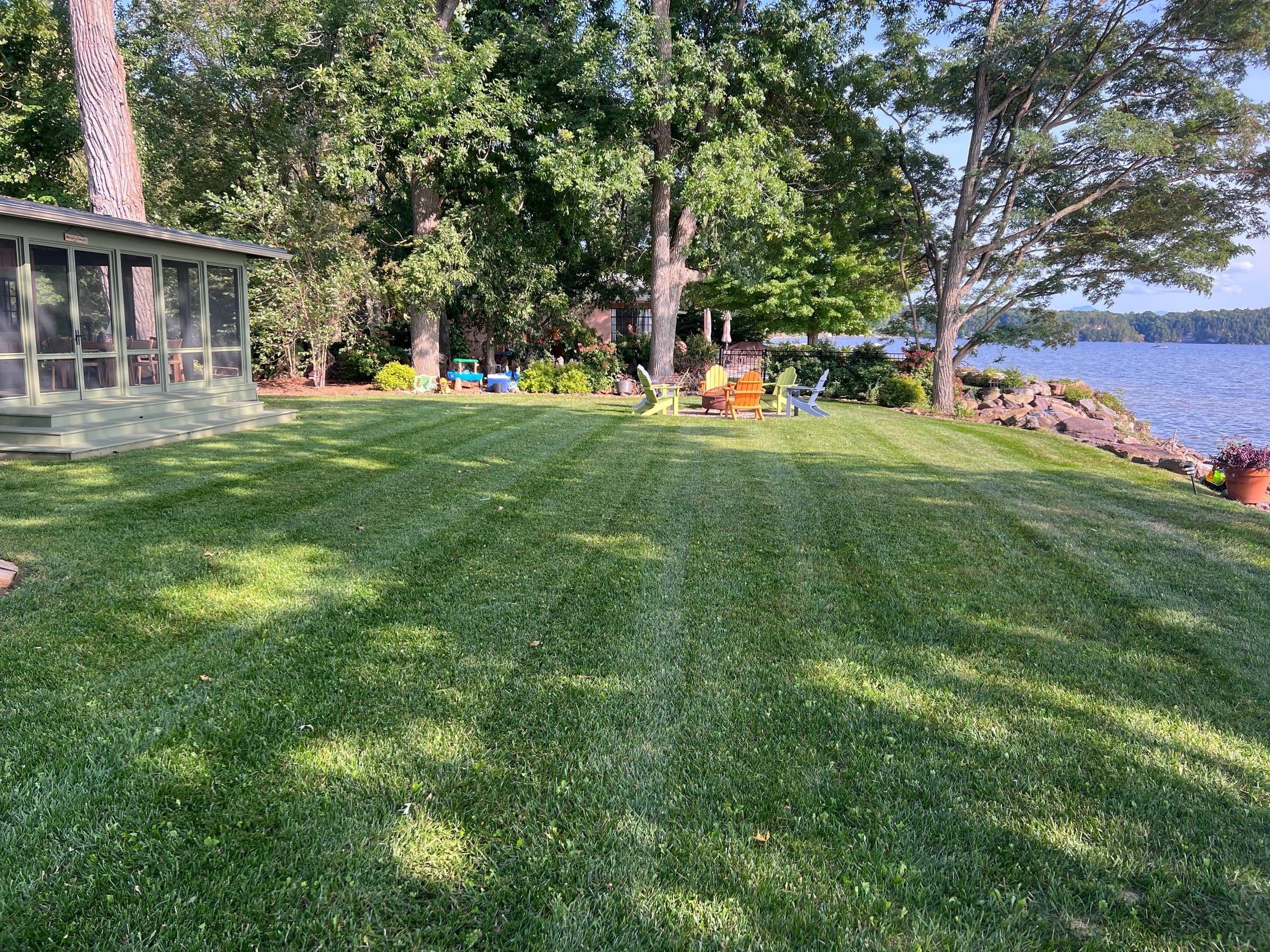 A striped green lawn running down to the lake
